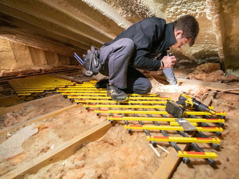 Technician working in an attic before new insulation goes in